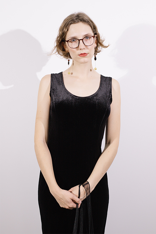 Девушка с очками в черном платье на бретелях.
